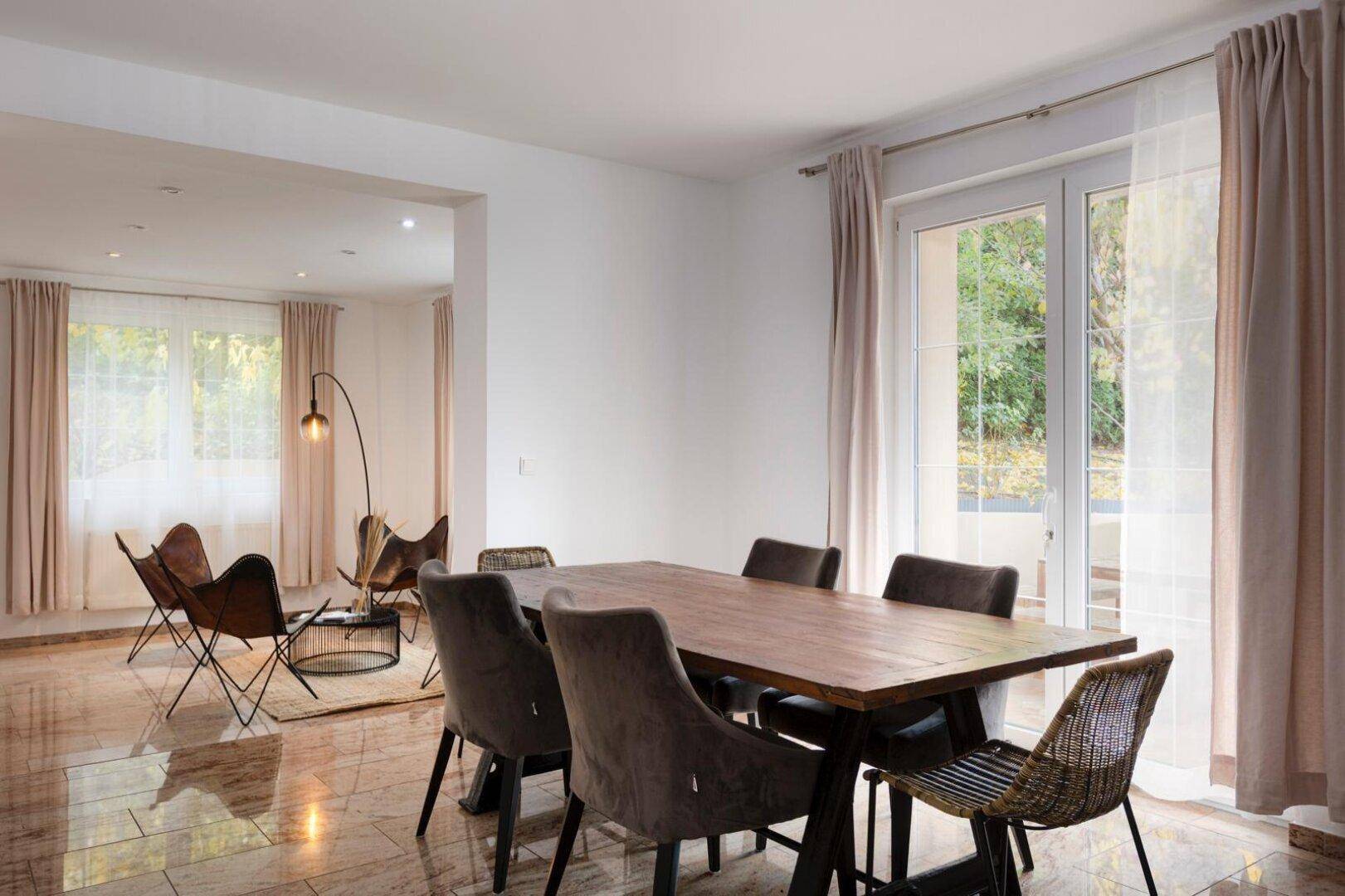 Heller Wohn- und Essbereich mit großem Holztisch, modernen Stühlen und Zugang zur Terrasse.