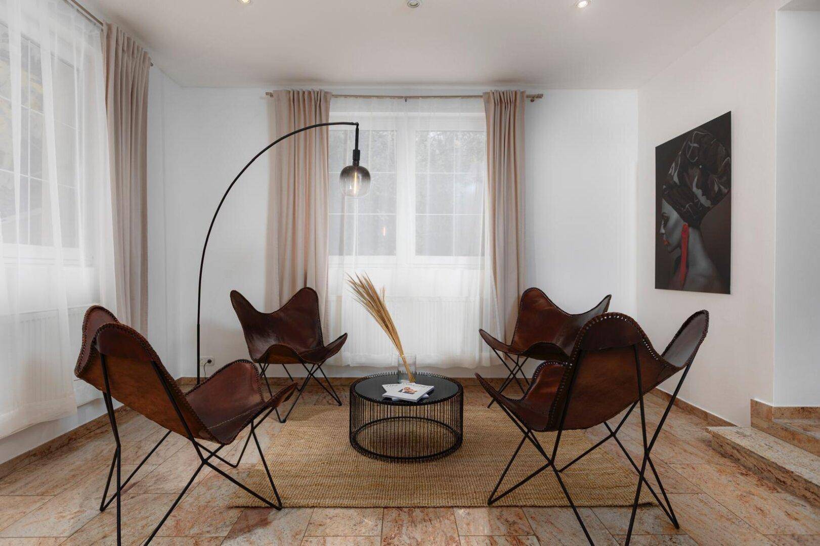 Gemütlicher Wohnbereich mit Ledersesseln, Couchtisch und Bogenlampe, auf Fliesenboden.