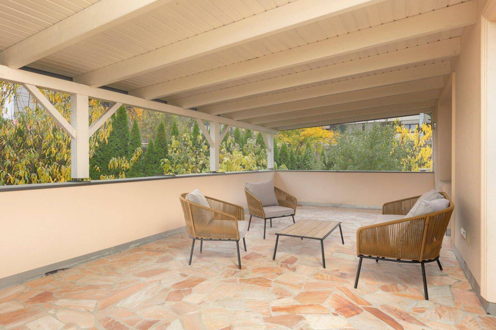 Überdachte Terrasse mit bequemen Loungemöbeln und Blick ins Grüne, ideal zum Entspannen.