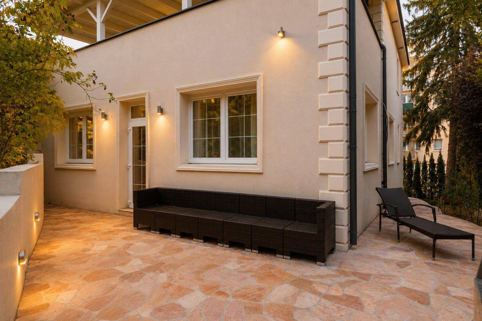 Geräumige Terrasse mit Steinboden und Loungemöbeln, ideal für entspannte Stunden im Freien.