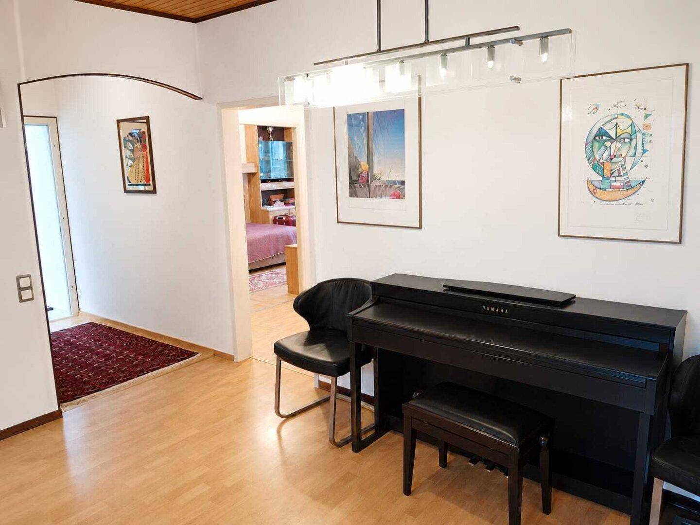 Heller Flur mit Holzboden, einem Klavier und Zugang zu weiteren Räumen im Haus.