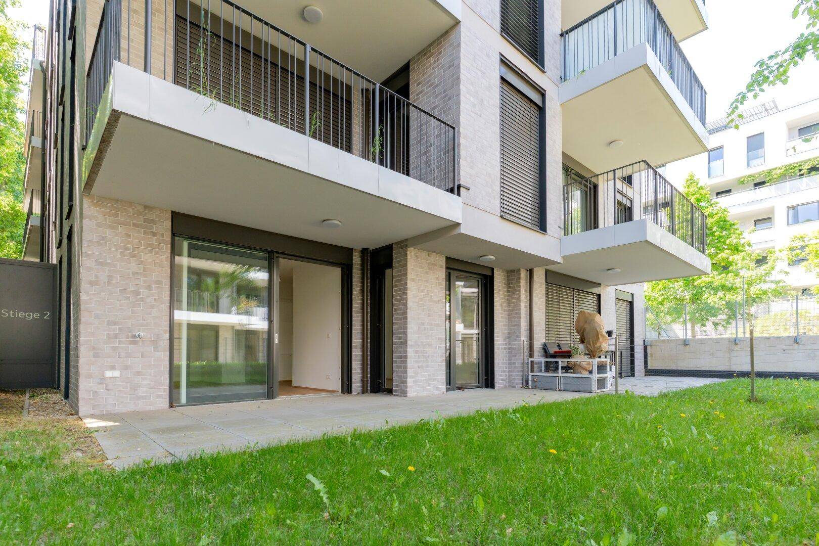 Neubau-Wohngebäude mit Terrassen und Balkonen, umgeben von gepflegten Grünflächen.