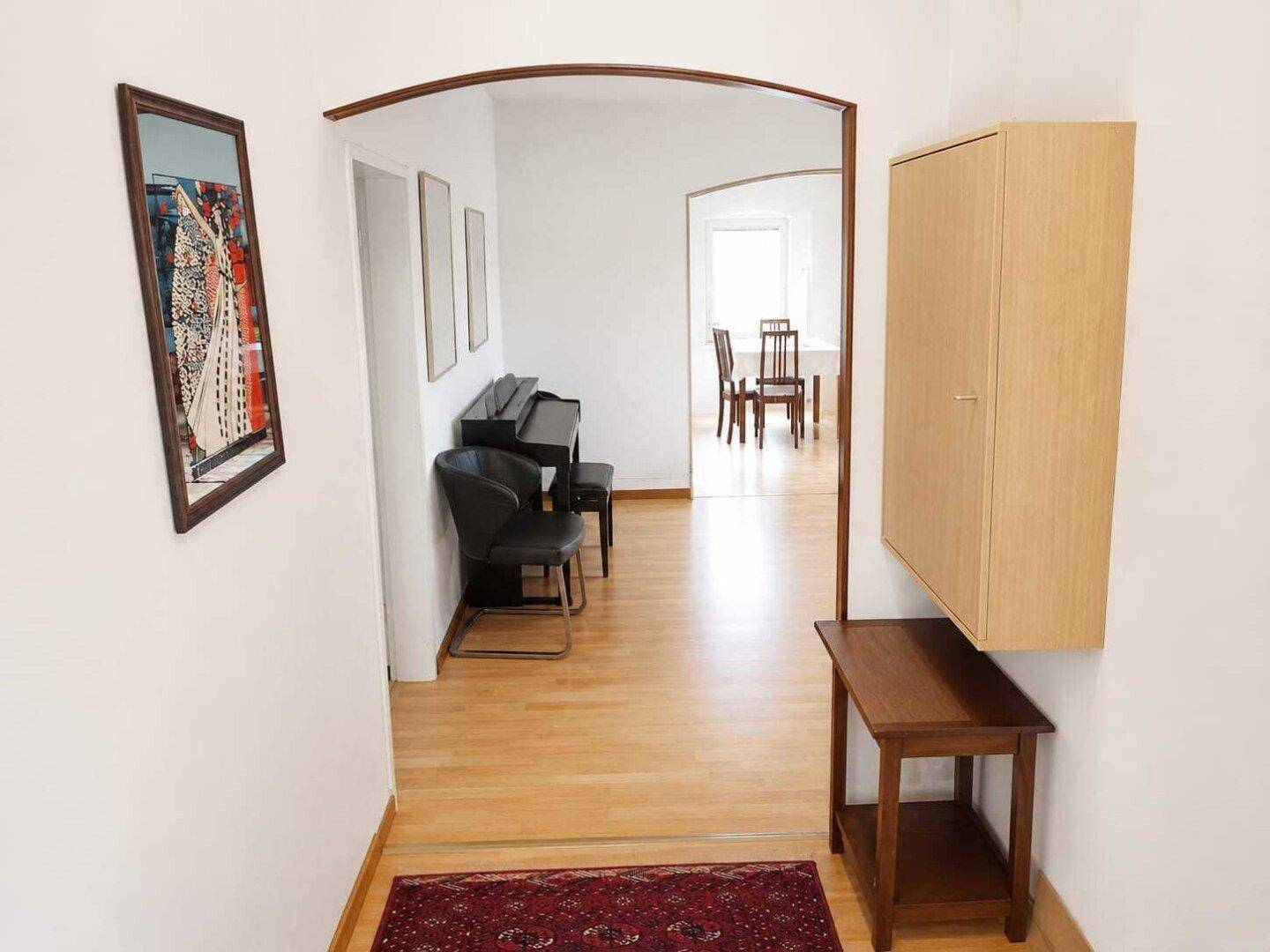 Langer Flur mit Holzboden, einem Schrank und Blick in den angrenzenden Essbereich.