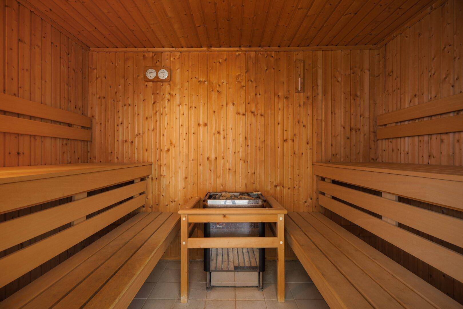Traditionelle Holzsauna mit Bänken und Saunaofen für entspannende Momente.