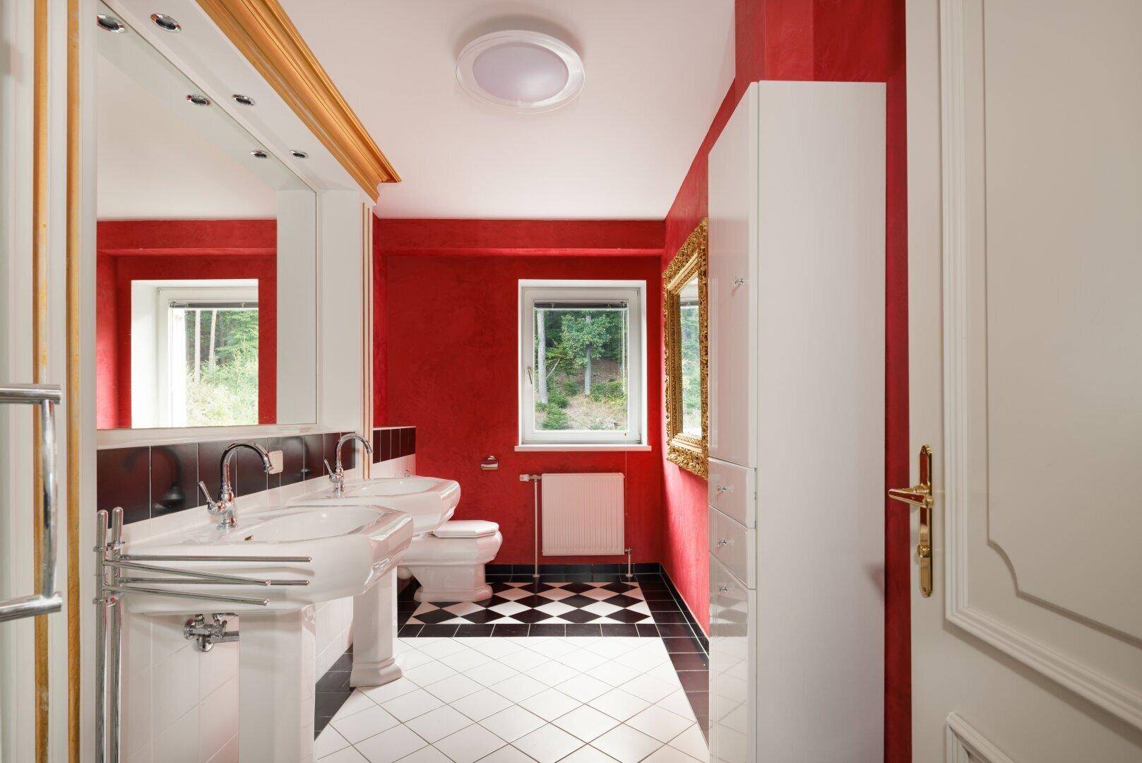 Farbiges Badezimmer mit Doppelwaschbecken, Fenster und auffälligen roten Wänden.