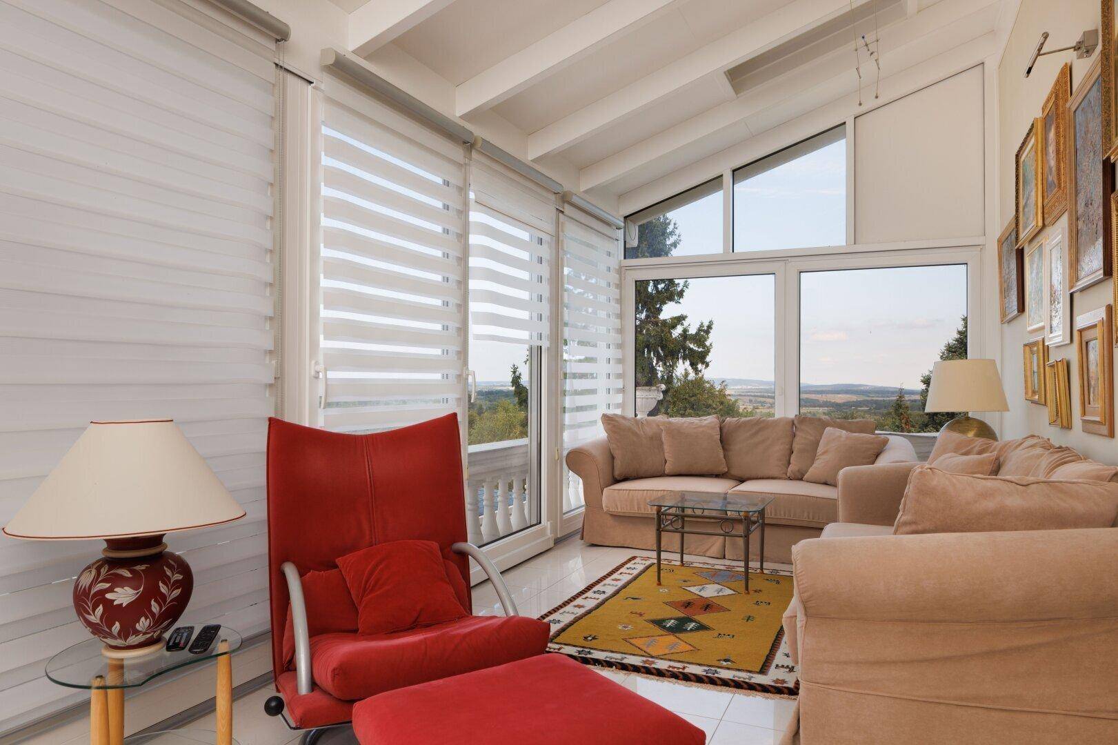 Helles Wohnzimmer mit großen Fenstern, die einen weiten Blick in die Landschaft bieten.