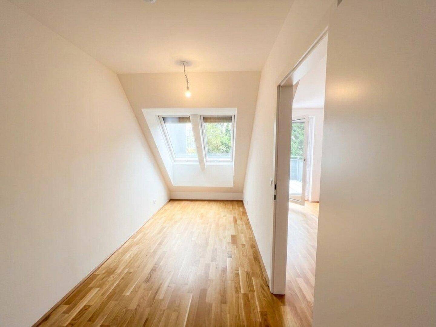 Heller Raum mit Holzboden, Dachschrägen und zwei Dachfenstern, bereit zur individuellen Gestaltung.