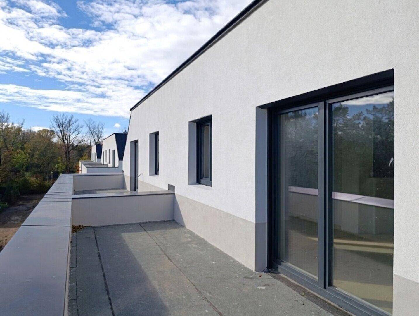 Blick von einem Balkon entlang der Fassade des Neubaus mit weitem Ausblick.