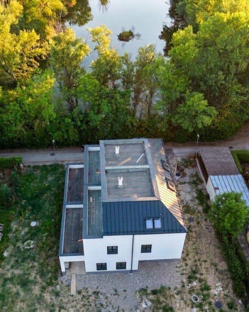 Vogelperspektive des Gebäudes mit Blick auf das Dach und die angrenzende Wasserfläche.