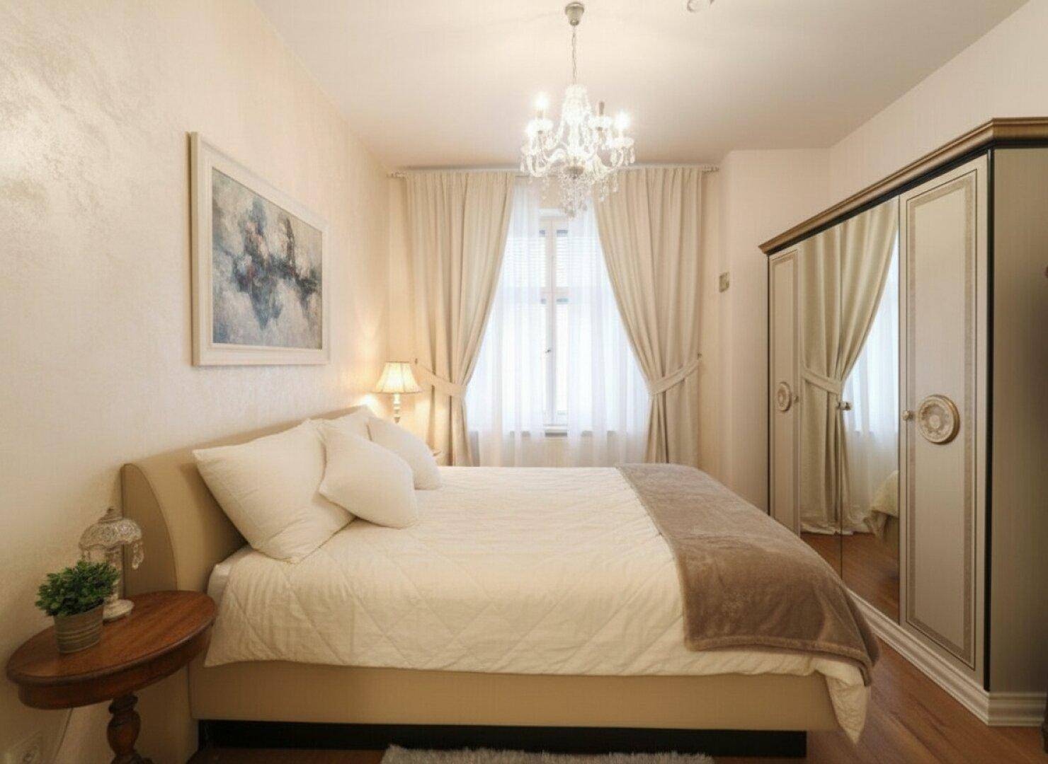 Gemütliches Schlafzimmer mit Doppelbett, Spiegelschrank und einem eleganten Kronleuchter an der Decke.