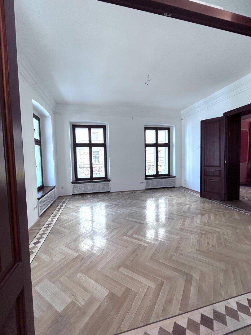 Heller Raum mit Fischgrätparkett und eleganten Holztüren, die in weitere Zimmer führen.