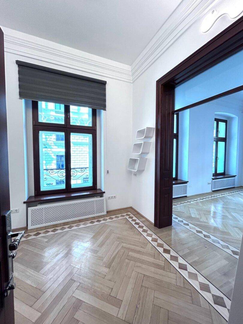 Heller Eingangsbereich mit Parkettboden, Fenster und dekorativen Wandregalen.