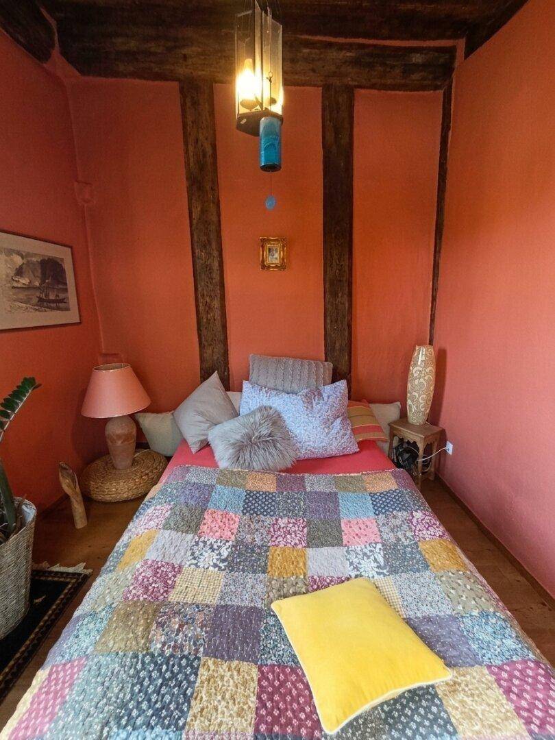 Gemütliches Schlafzimmer mit freiliegenden Holzbalken, warmen Farben und Patchwork-Decke.