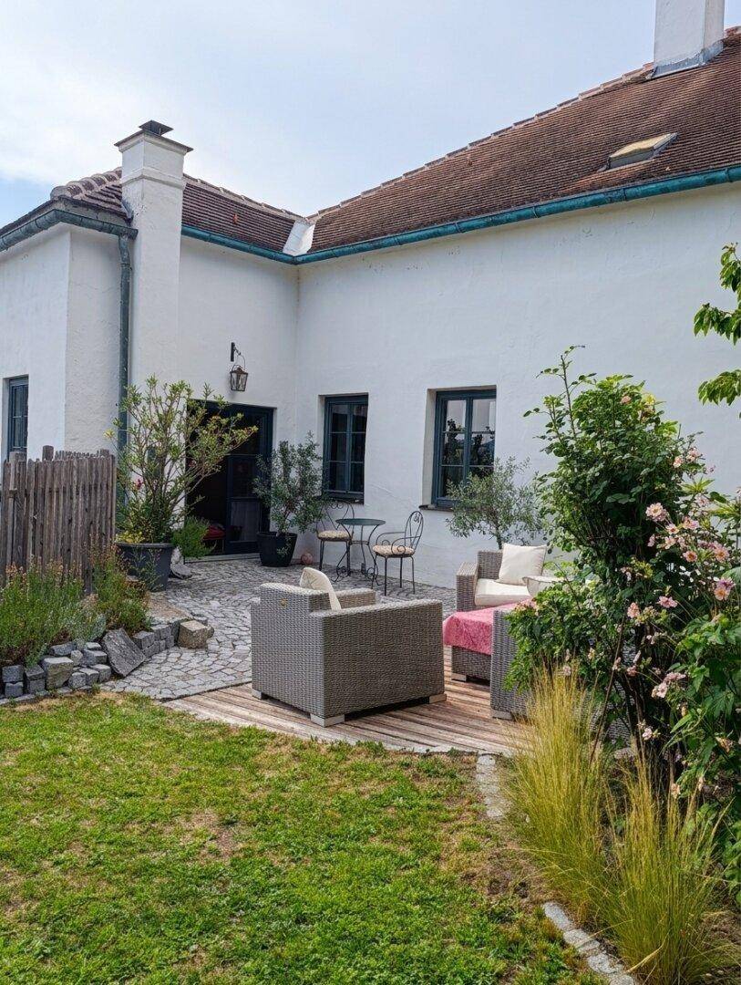 Gepflegter Garten mit Rasenfläche, Outdoor-Sitzgruppe und Blick auf die Hausfassade.