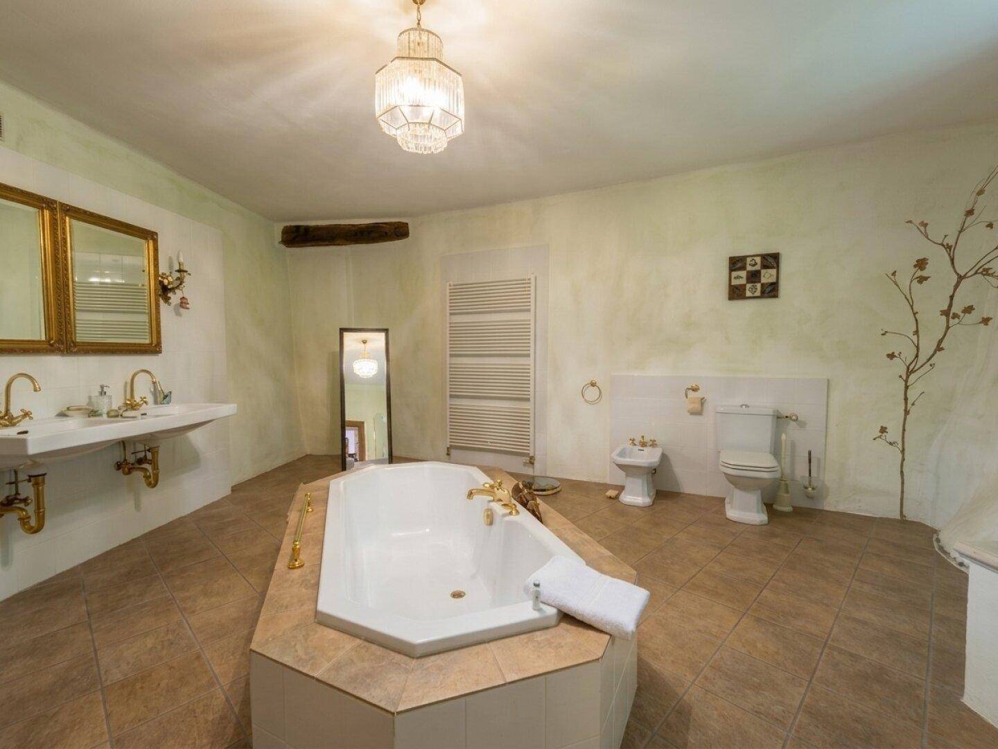 Geräumiges Badezimmer mit freistehender Badewanne, Doppelwaschbecken, Bidet und WC.