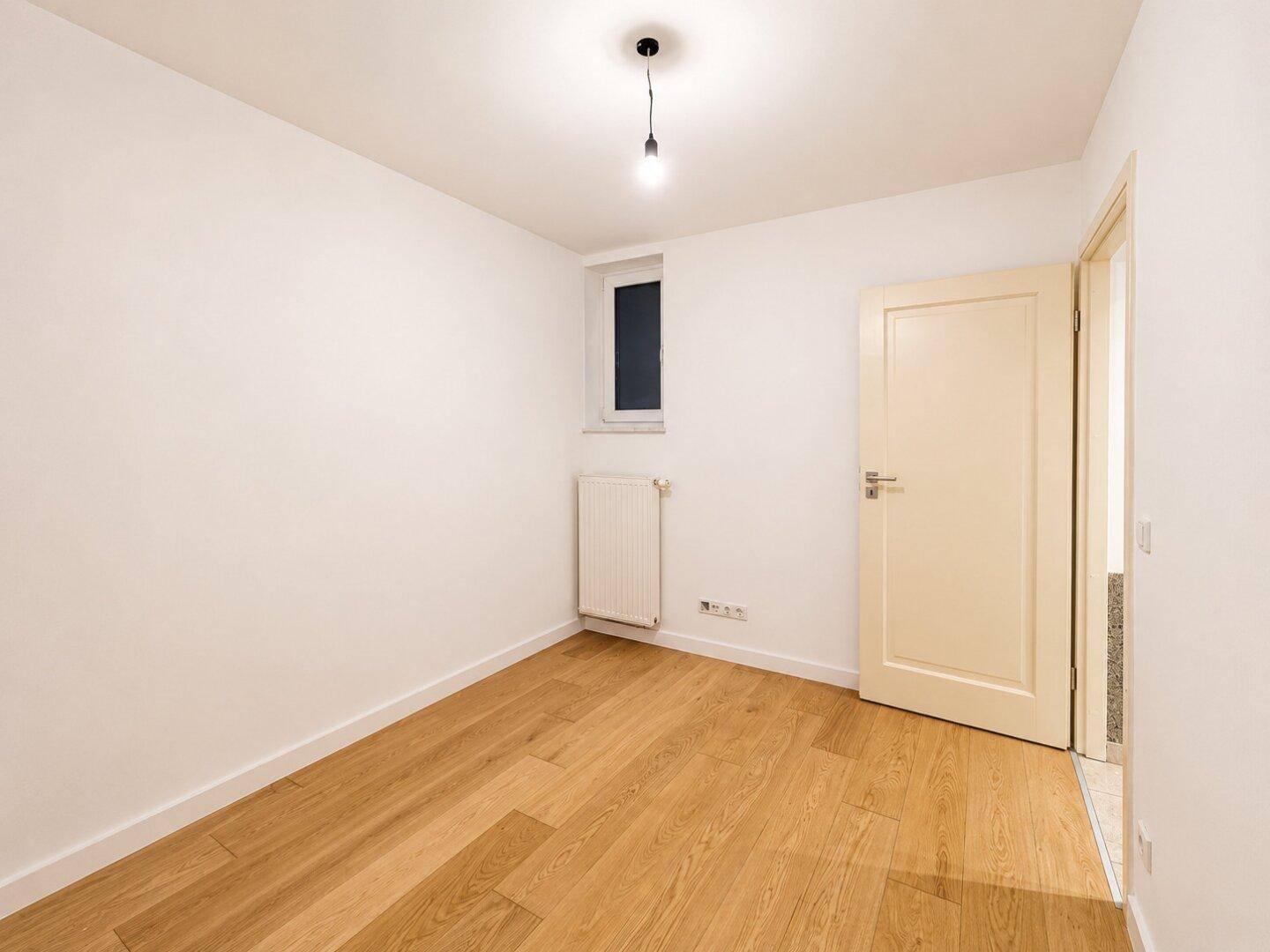 Helles Zimmer mit Holzboden und Fenster, ideal als Schlaf- oder Arbeitszimmer.
