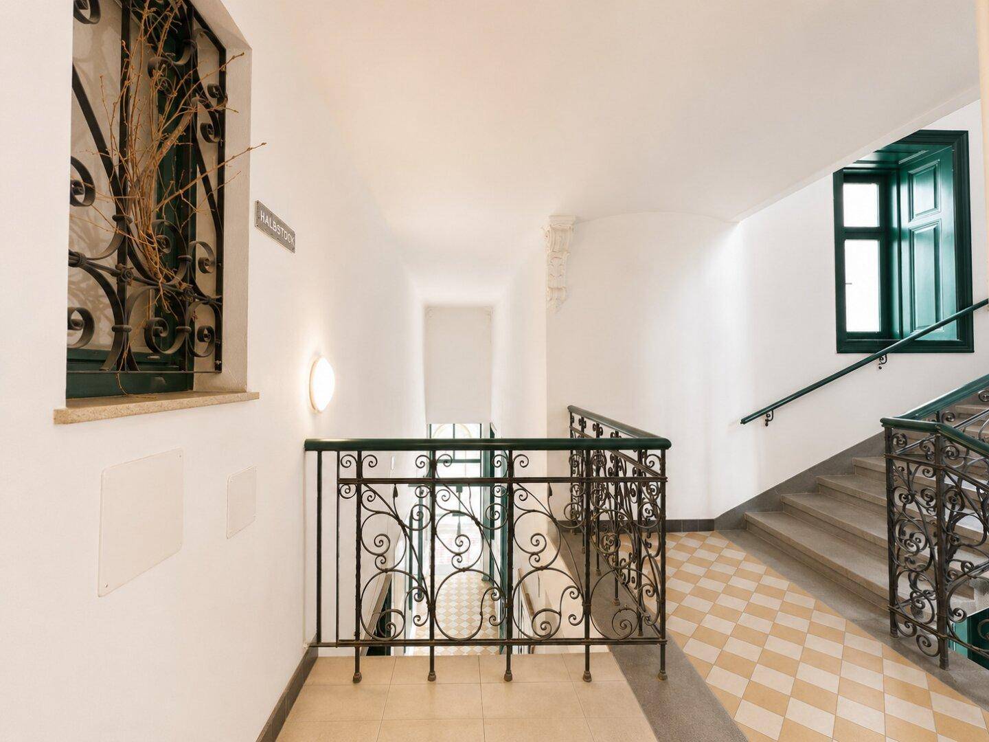 Elegantes Treppenhaus mit schmiedeeisernem Geländer und traditionellem Fliesenmuster.