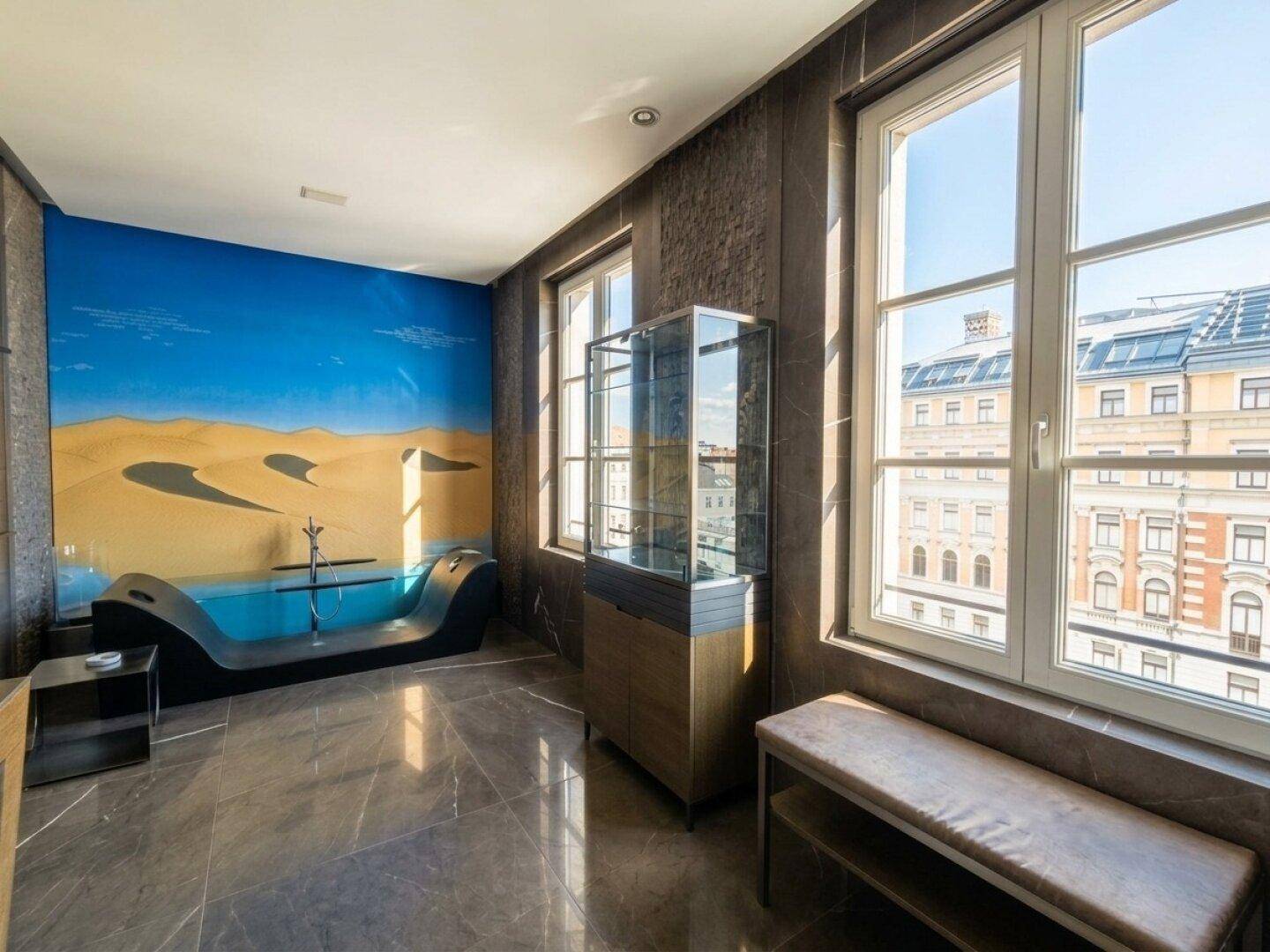 Luxuriöses Badezimmer mit großer Badewanne, dunklen Fliesen und großen Fenstern.