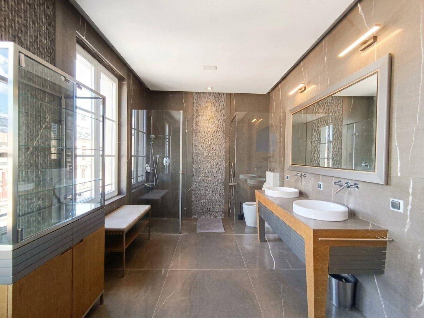 Modernes Badezimmer mit Doppelwaschbecken, begehbarer Dusche und großen Fenstern.