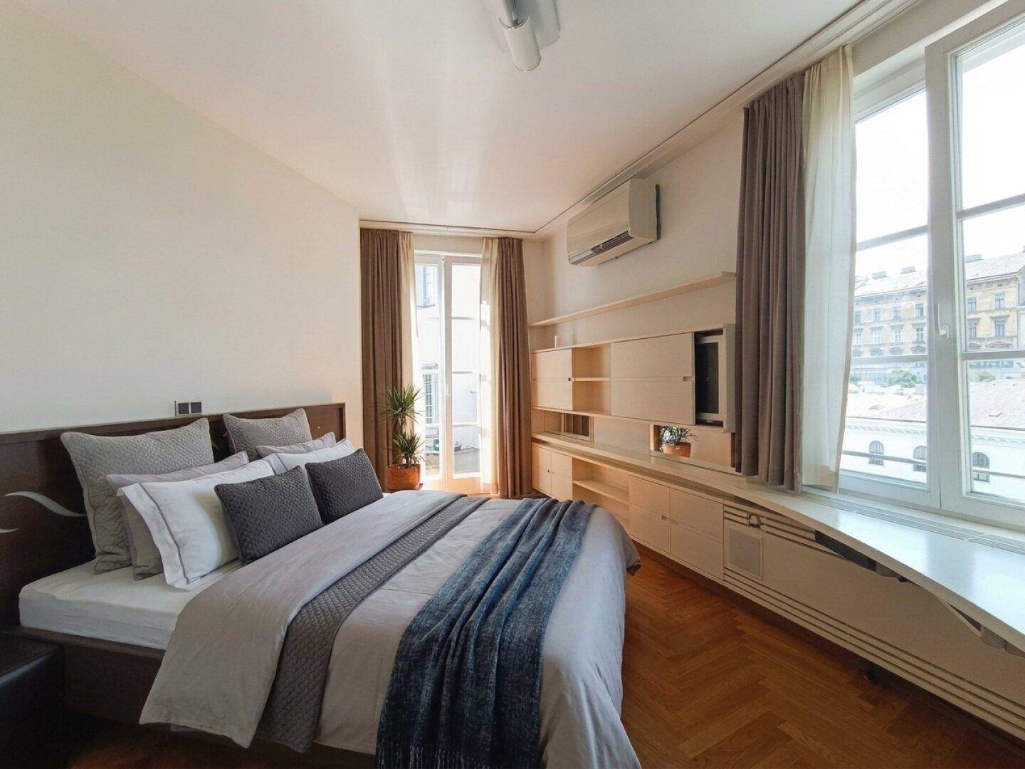 Gemütliches Schlafzimmer mit Holzbett, Fischgrätparkett und Zugang zu einem Balkon.