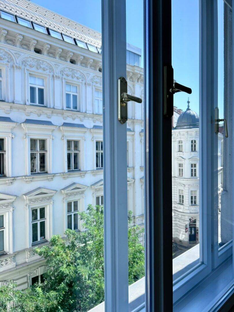 Blick aus dem Fenster auf die historische Architektur der umliegenden Gebäude und die grüne Umgebung.