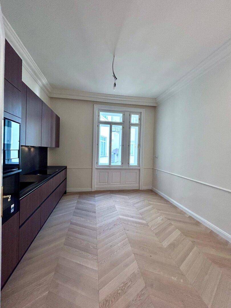 Geräumige Küche mit moderner Einbauzeile, Fischgrätparkett und einem großen Fenster für Tageslicht.
