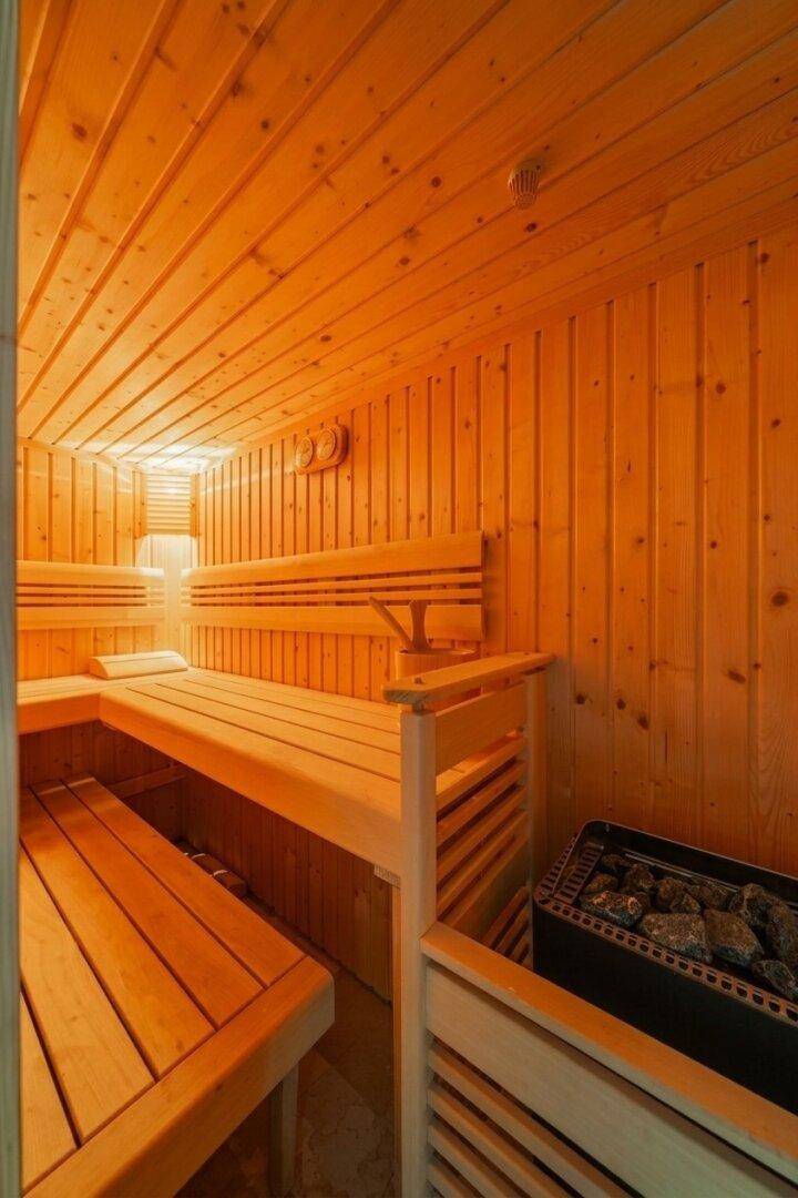 Gemütlicher Saunaraum aus Holz mit mehreren Bänken und einem traditionellen Saunaofen.