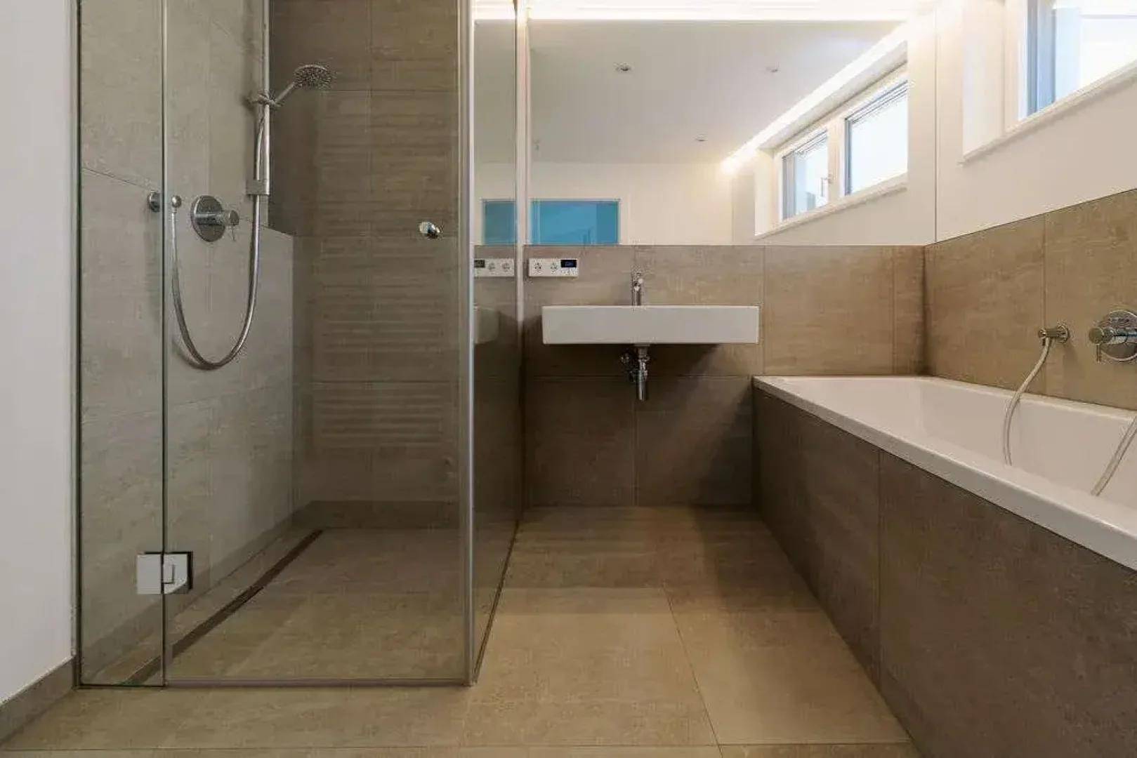 Modernes Badezimmer mit begehbarer Dusche, Badewanne und beigefarbenen Fliesen.