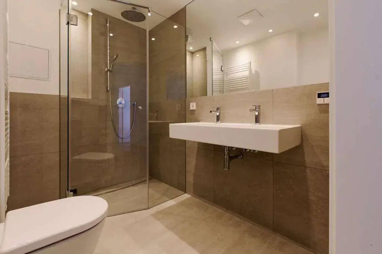 Modernes Badezimmer mit begehbarer Dusche, Doppelwaschbecken und Wand-WC.