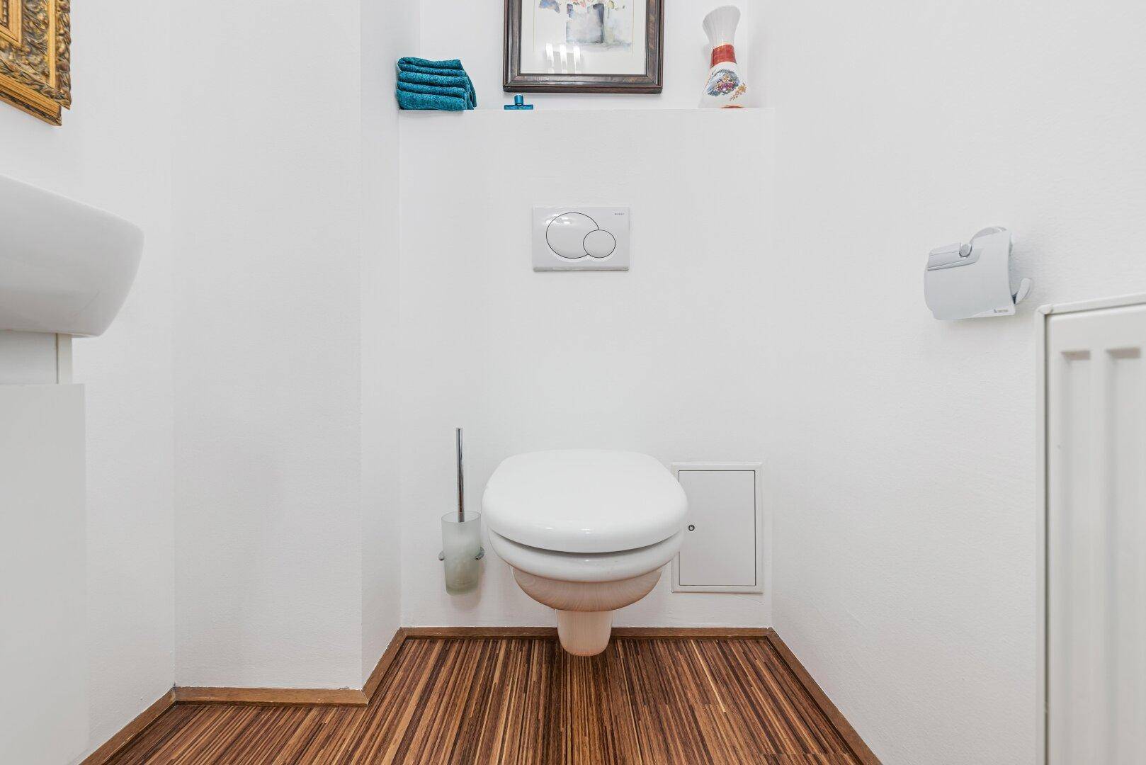 Modernes Gäste-WC mit wandhängendem WC und Holzboden, hell und funktional.