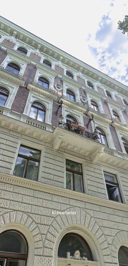 Historische Fassade eines Gebäudes mit verzierten Balkonen und großen Fenstern unter blauem Himmel.