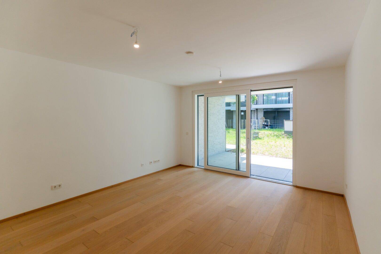 Geräumiger Wohnbereich mit Holzdielenboden und großer Schiebetür zur Terrasse.