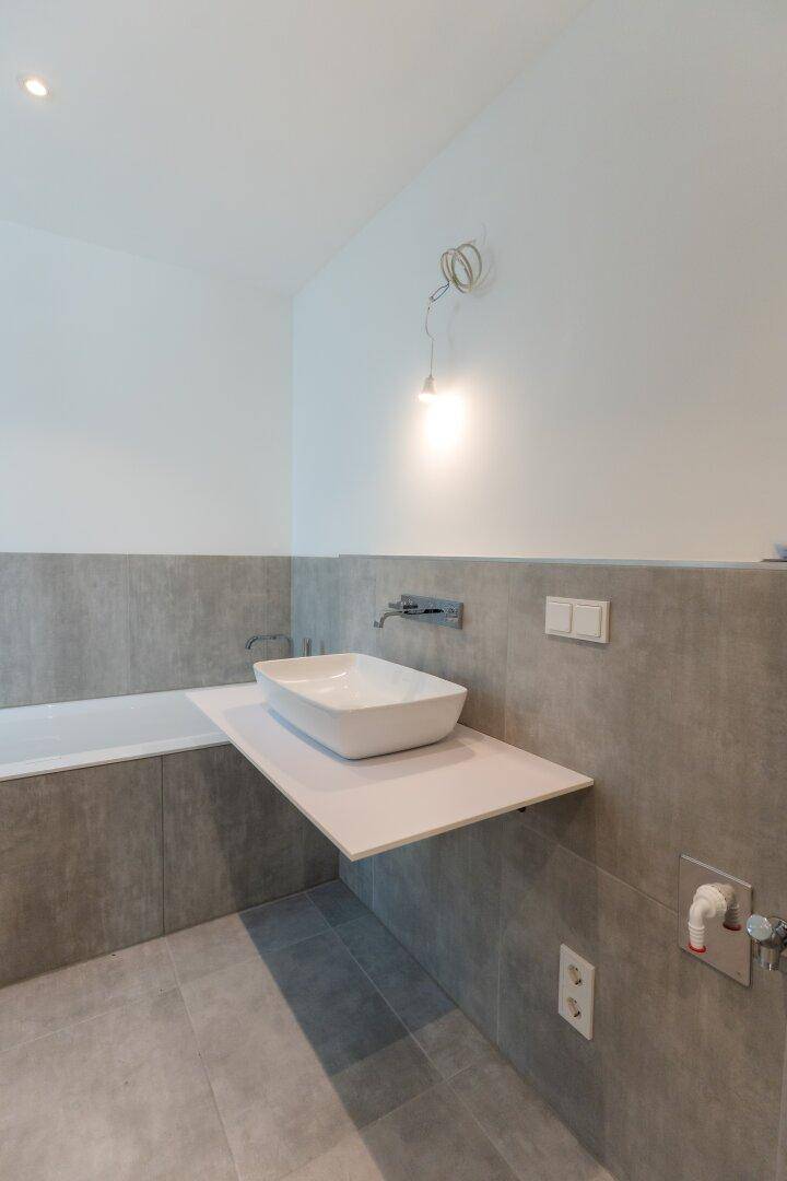 Detailansicht des modernen Badezimmers mit stilvollem Waschbecken und integrierter Badewanne.