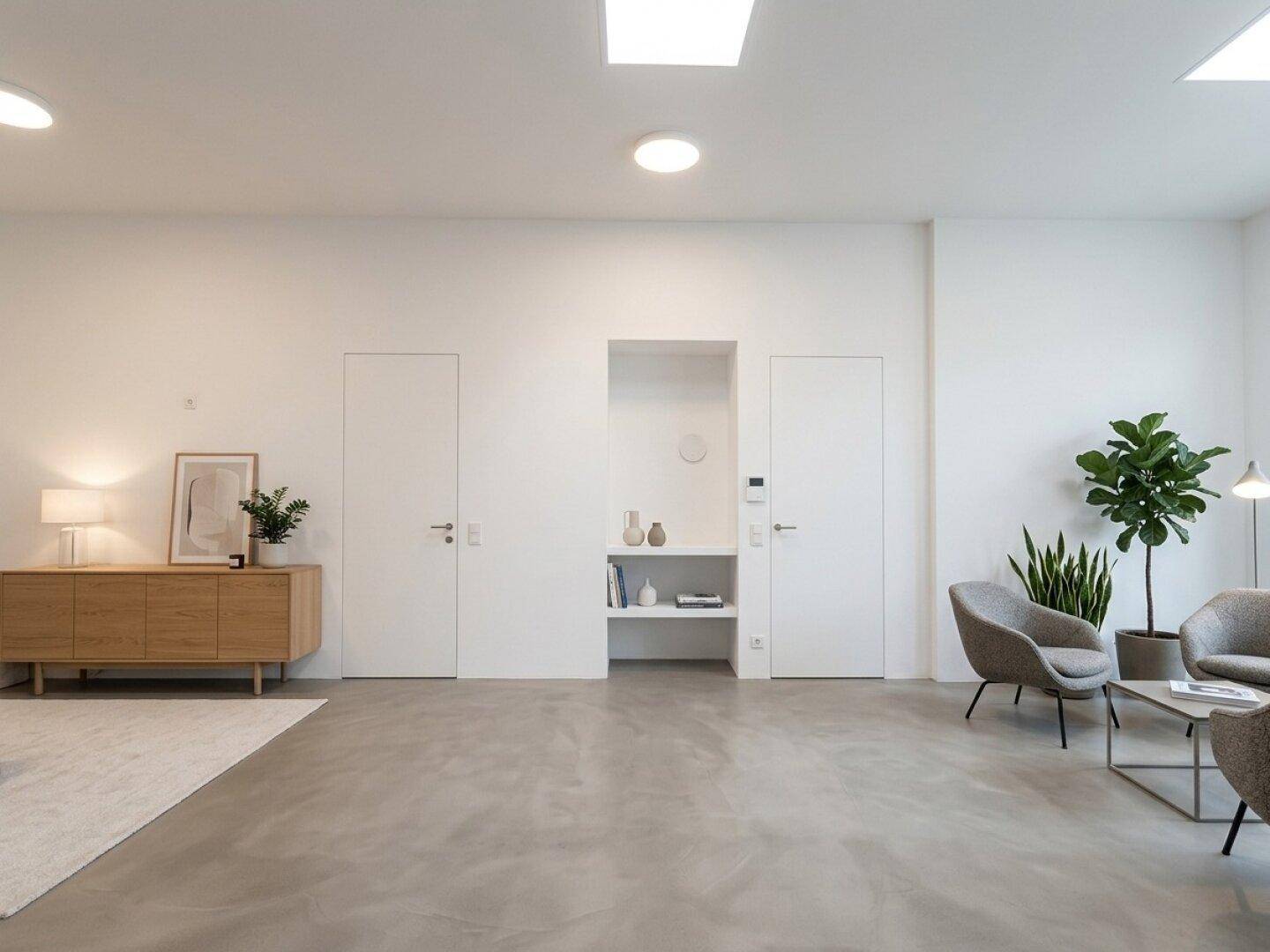 Minimalistischer Raum mit hellem Betonboden, weißen Wänden und modernen Sitzgelegenheiten.