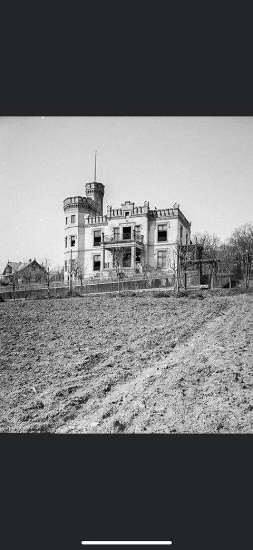 Historisches Schwarz-Weiß-Foto des Gebäudes mit Turm und umliegendem Gelände.