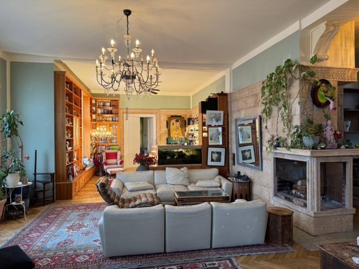 Elegantes Wohnzimmer mit Kamin, bequemen Sofas, Parkettboden und umfangreichen Bücherregalen.