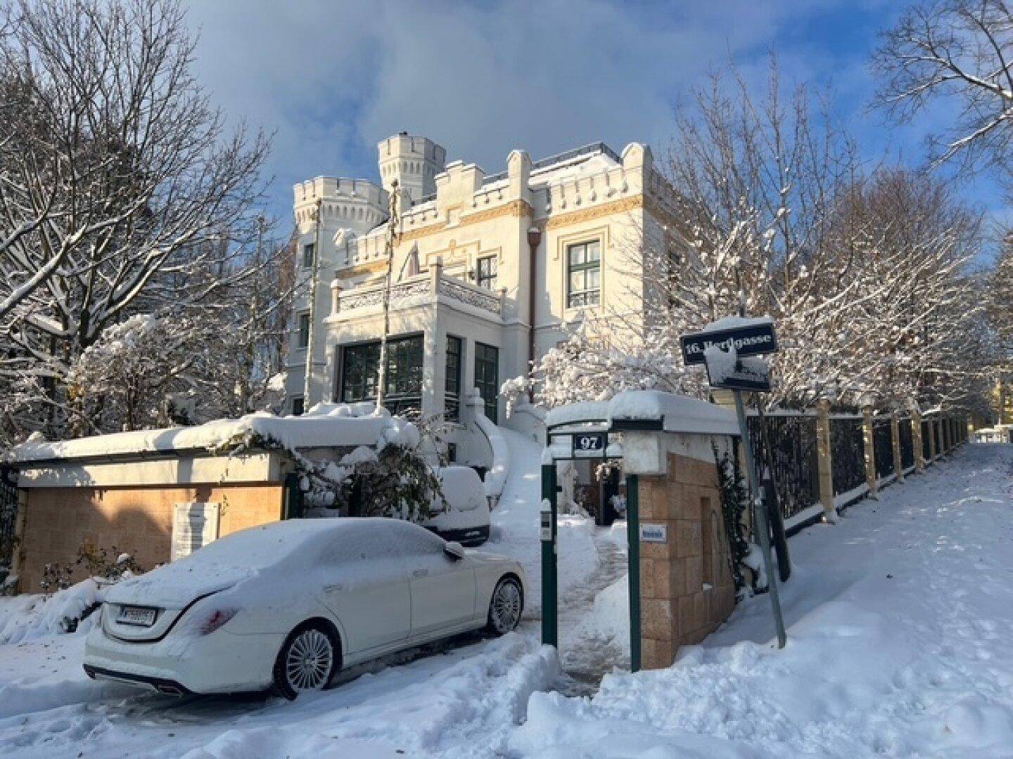 Historisches Gebäude im Winter, bedeckt mit Schnee, umgeben von verschneiten Bäumen.