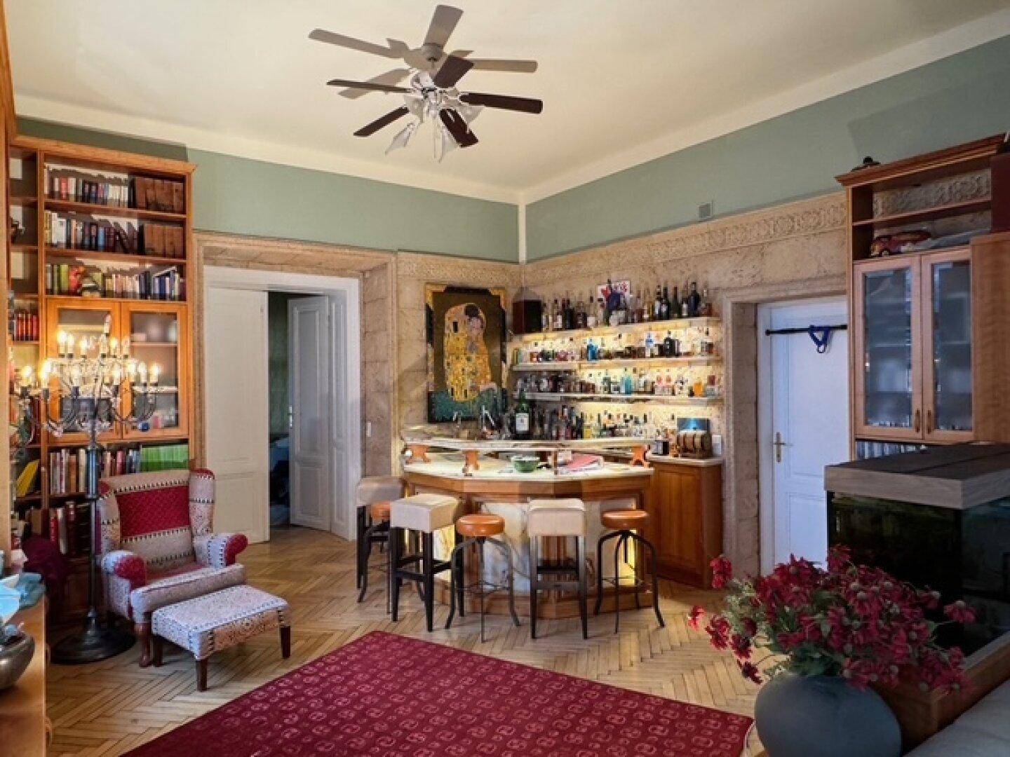 Stilvolle Bar im Wohnzimmer mit beleuchteten Regalen, Hockern und Parkettboden.