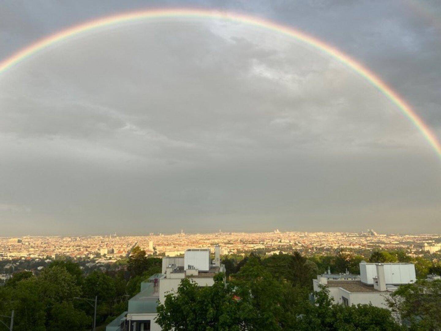 Weitblick über die Stadt mit einem beeindruckenden Regenbogen am Himmel.