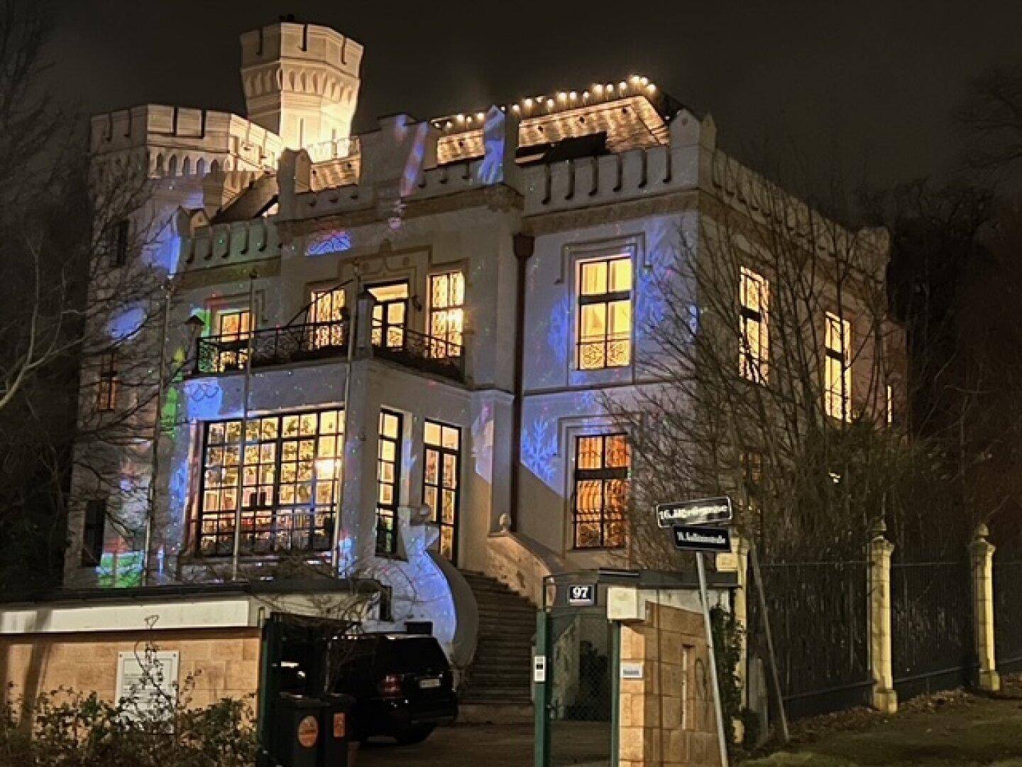 Historisches Gebäude bei Nacht, festlich beleuchtet mit Projektionen und Lichterketten.