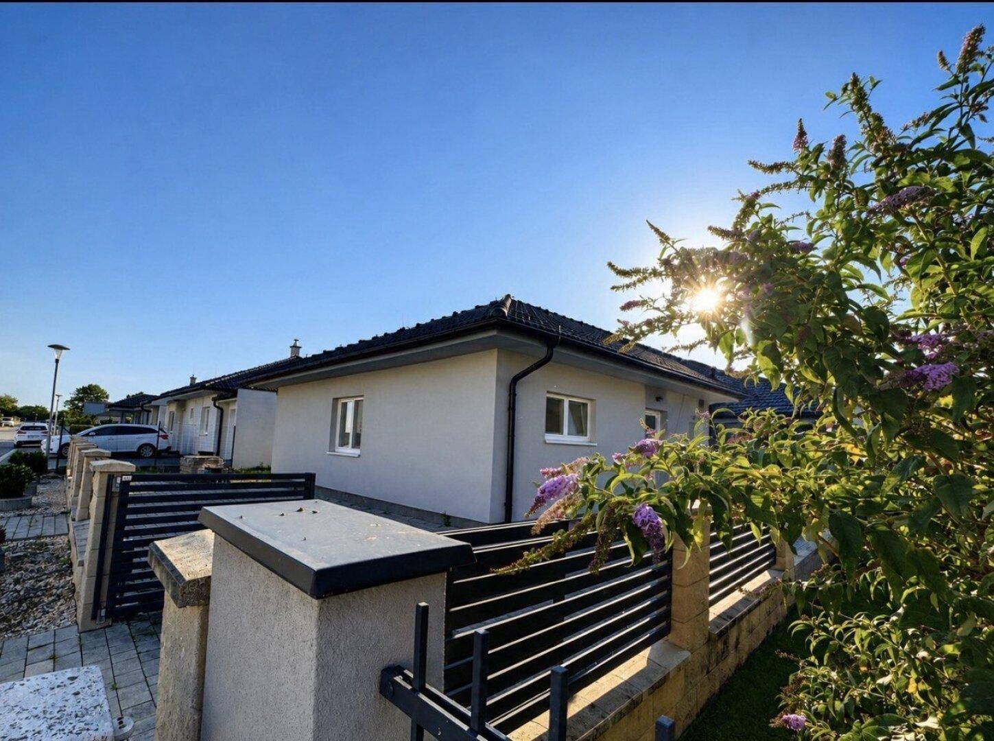 Moderne Einfamilienhäuser in einer ruhigen Wohngegend unter strahlend blauem Himmel.