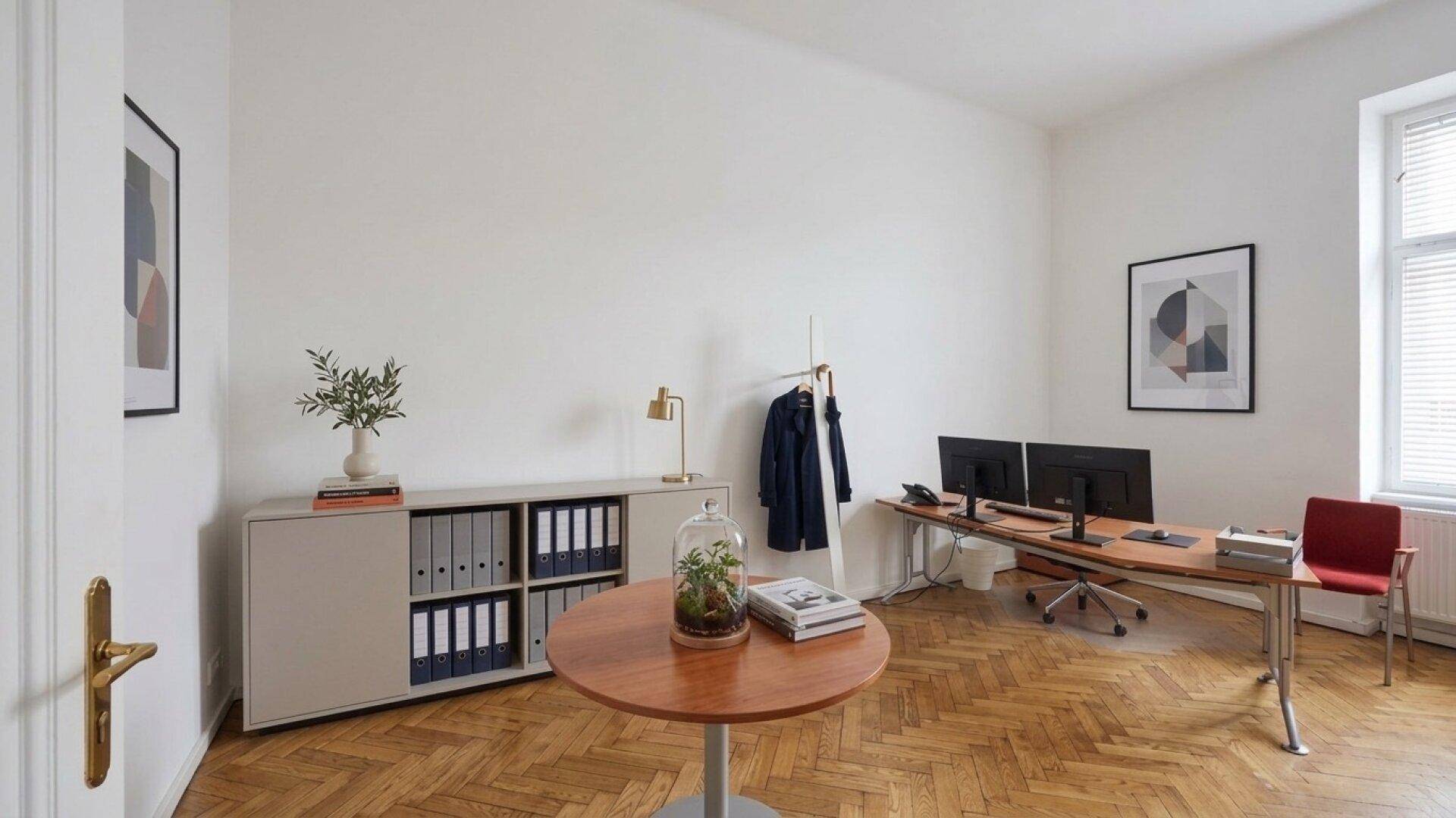 Helles Büro mit Schreibtisch, zwei Monitoren und Fischgrätparkettboden.