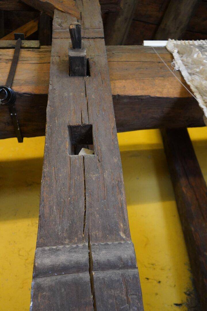 Detailaufnahme eines massiven, alten Holzbalkens mit einer Aussparung, Teil der historischen Bausubstanz.