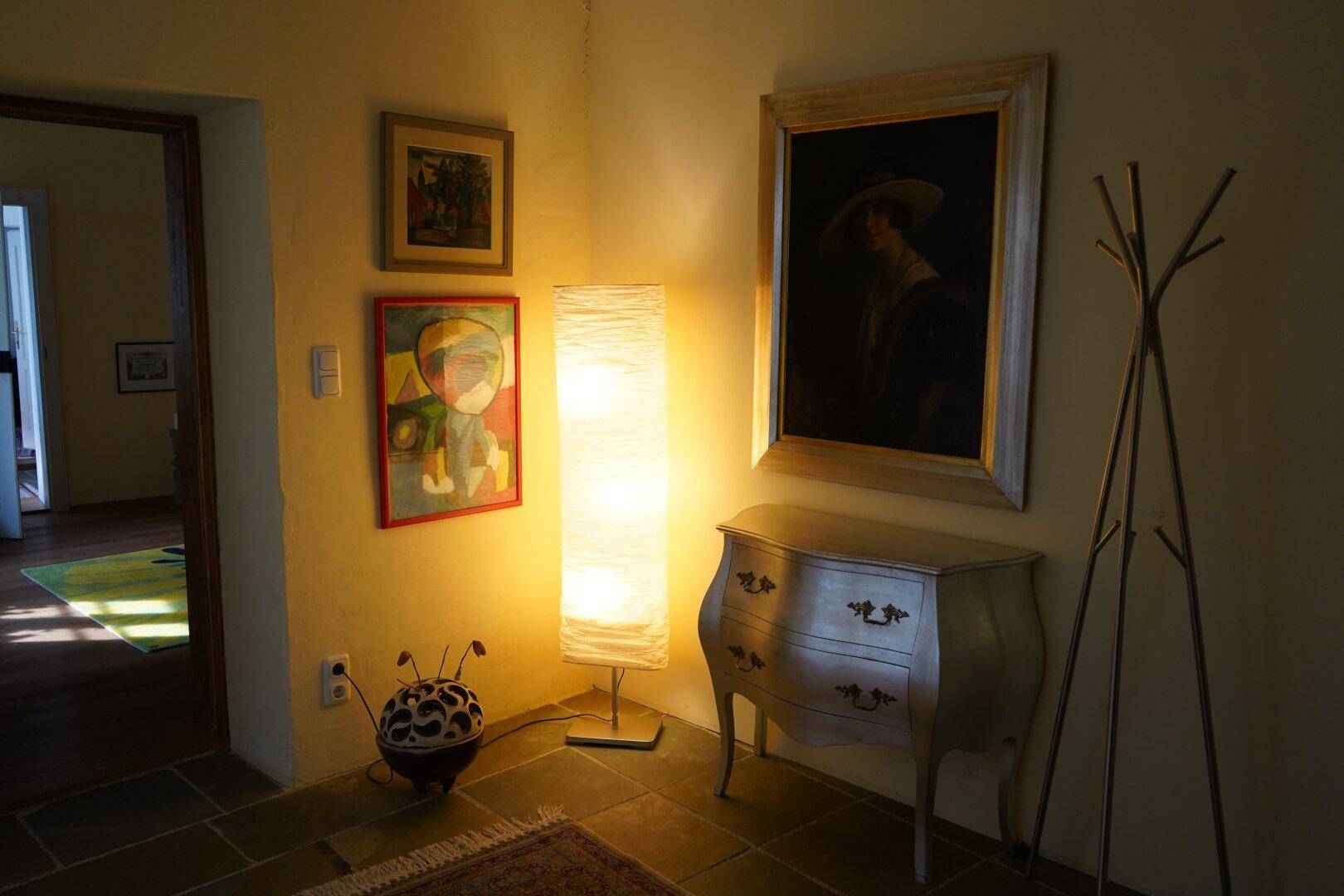 Flur mit einer modernen Stehlampe, einem Kommode und Kunstwerken an den Wänden.