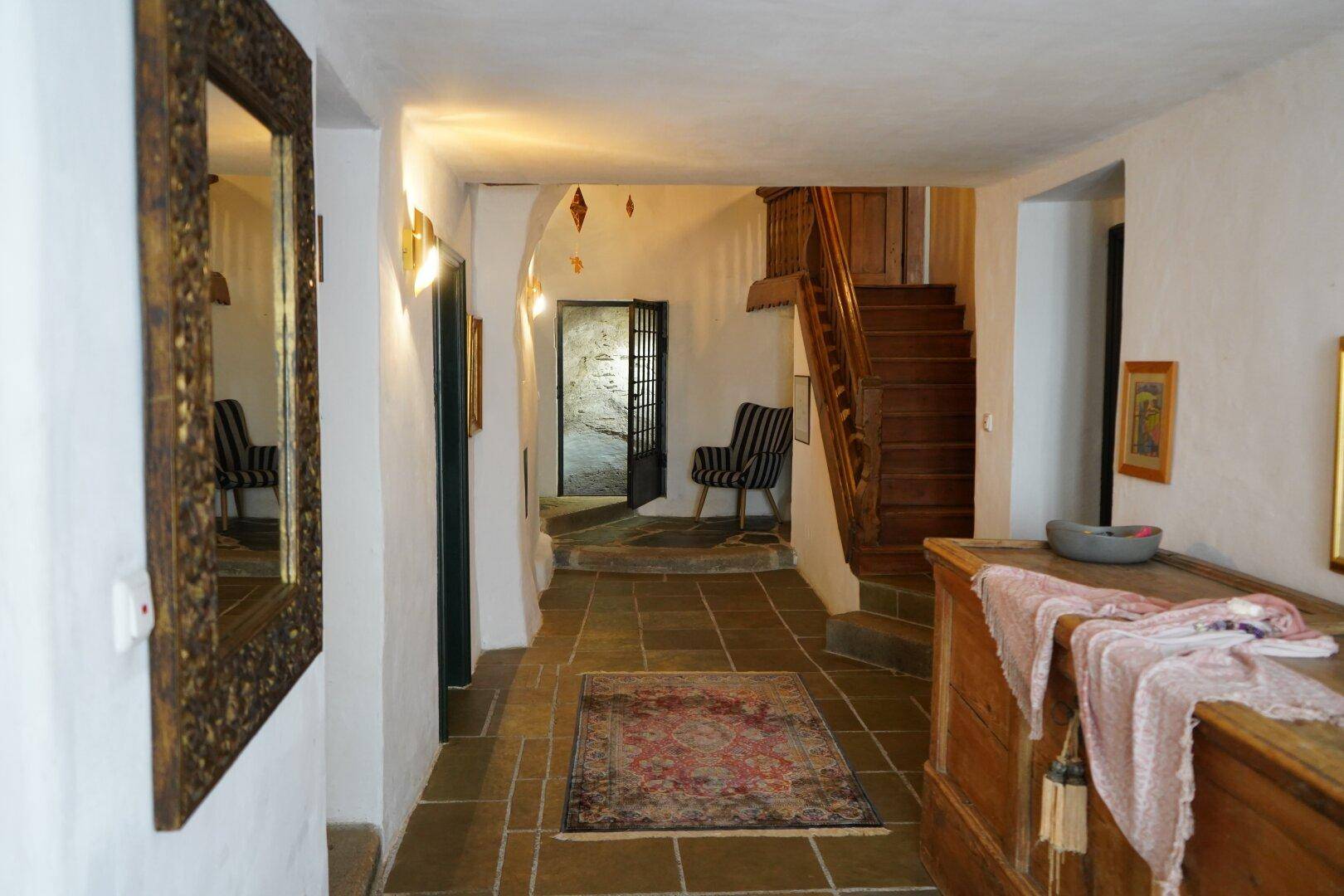 Geräumiger Flur mit einer Holztreppe, antiken Möbeln und gefliestem Boden.