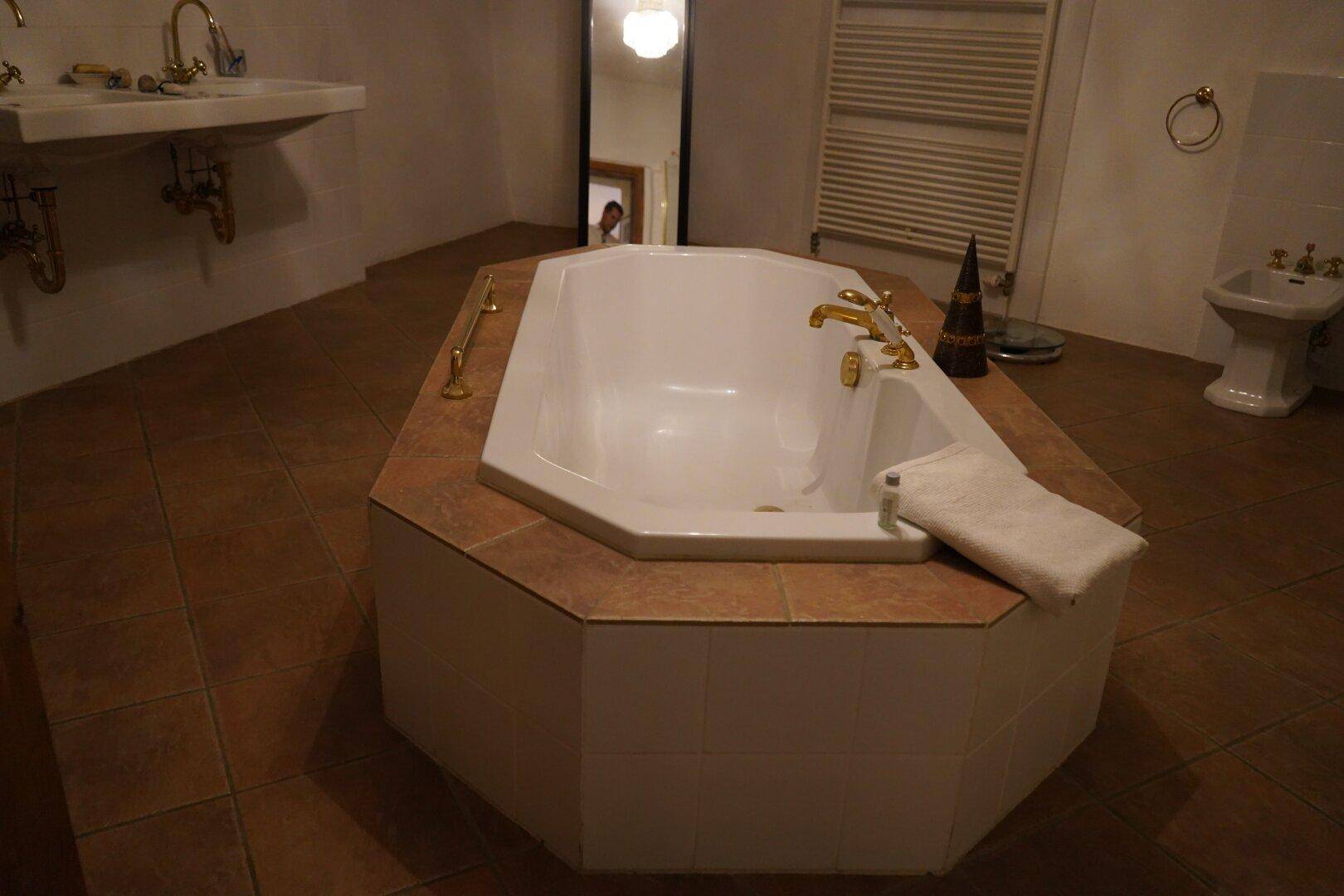 Geräumiges Badezimmer mit einer gefliesten Badewanne, Bidet und Heizkörper.