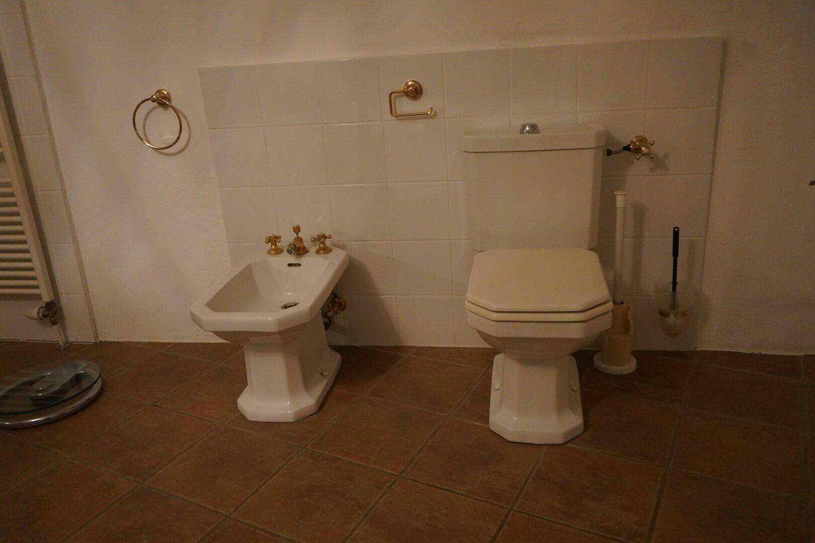 Badezimmer mit Toilette, Bidet und gefliestem Boden in warmen Terrakotta-Tönen.
