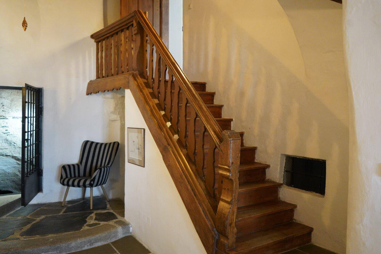Rustikale Holztreppe mit geschnitztem Geländer, die in die oberen Stockwerke führt.
