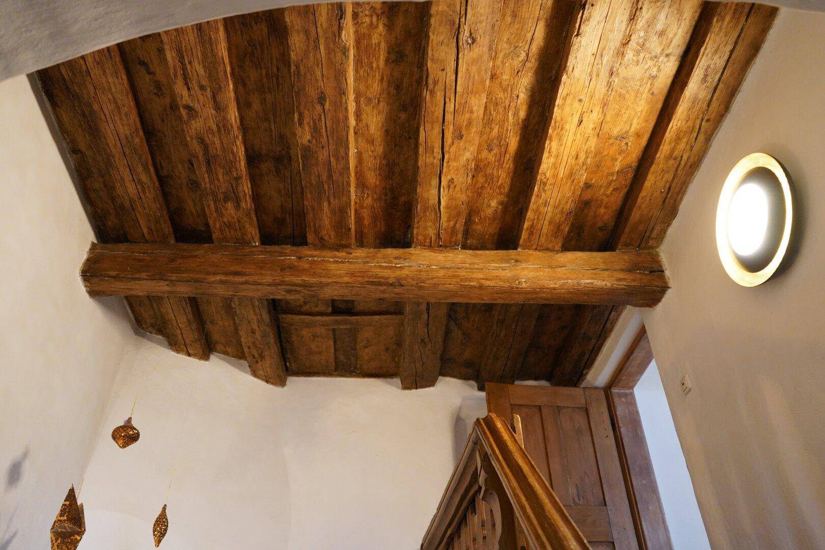 Rustikale Holzdecke mit sichtbaren Balken und Dielen, die den traditionellen Charme unterstreicht.