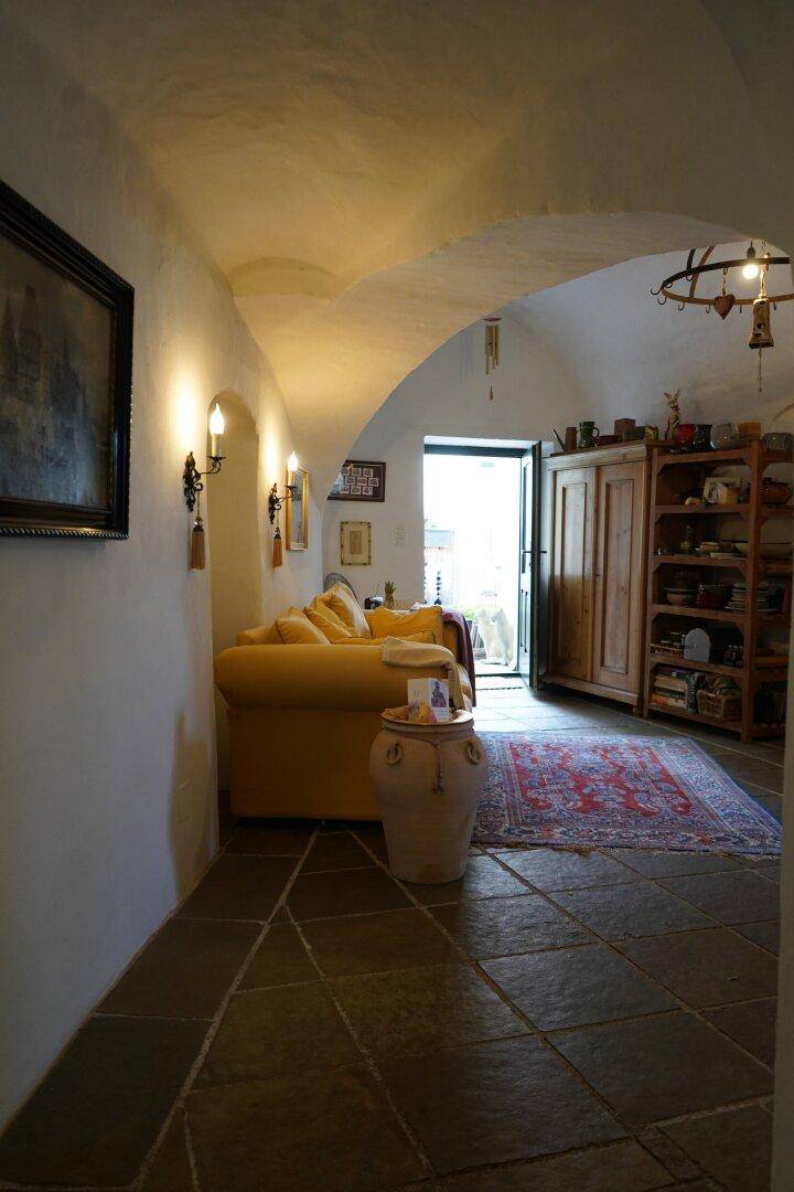 Wohnzimmer mit gelbem Sofa, Gewölbedecke und gefliestem Boden, mit Zugang zum Außenbereich.